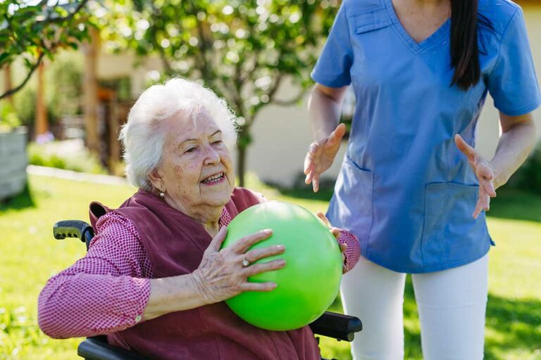 A group of family members greeting an older adult in a well-lit assisted living lounge.