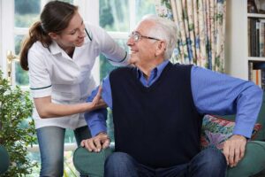 Older adult arranging photographs and a favorite chair in a new assisted living room.